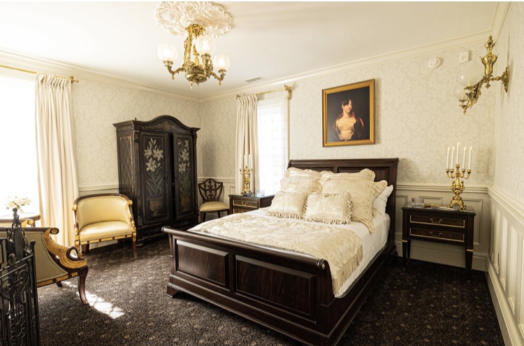 Cream-colored bedroom with bed, boudoir, bedside tables and chairs 