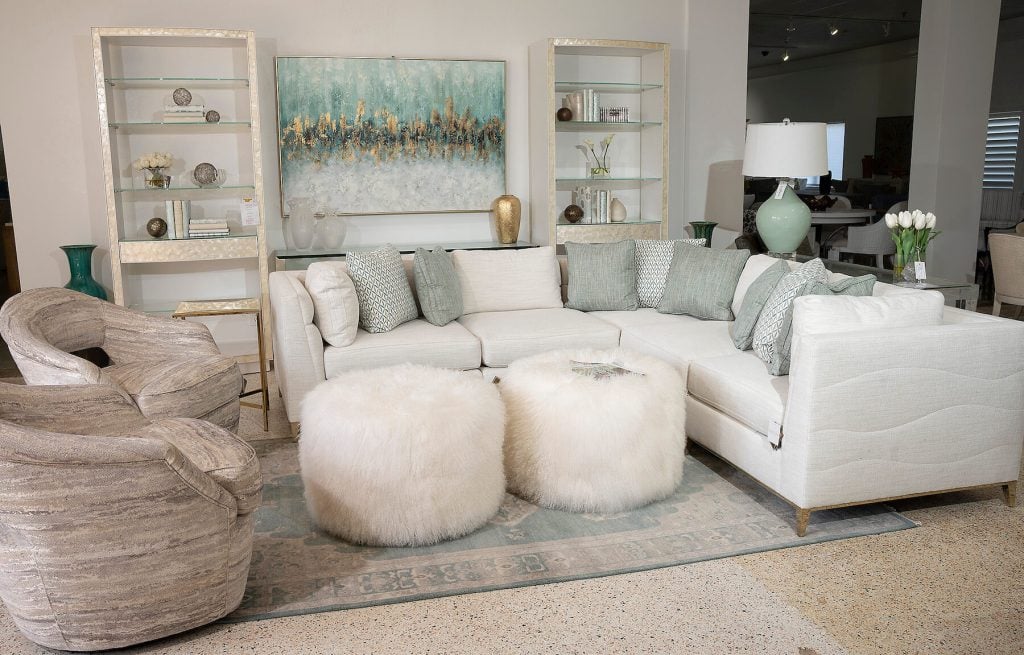 A white sectional and white fuzzy ottomans.