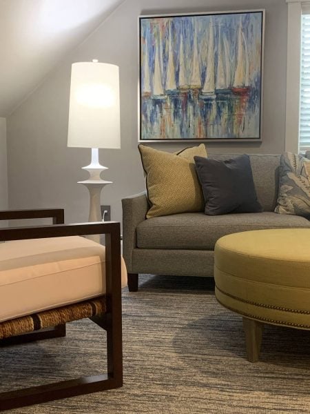 Sofa, ottoman, and chair with a lamp and a sailboat painting in the background