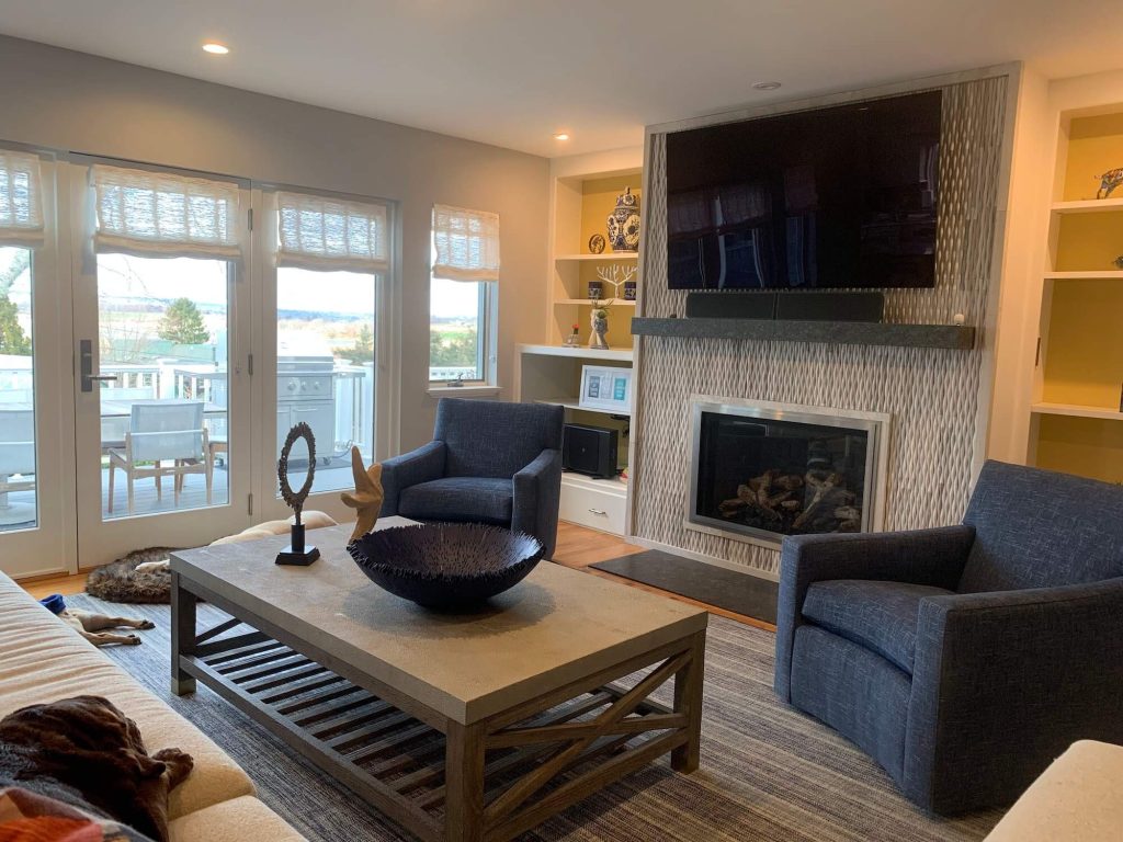 Living room with two chairs, coffee table, and TV mounted over fireplace