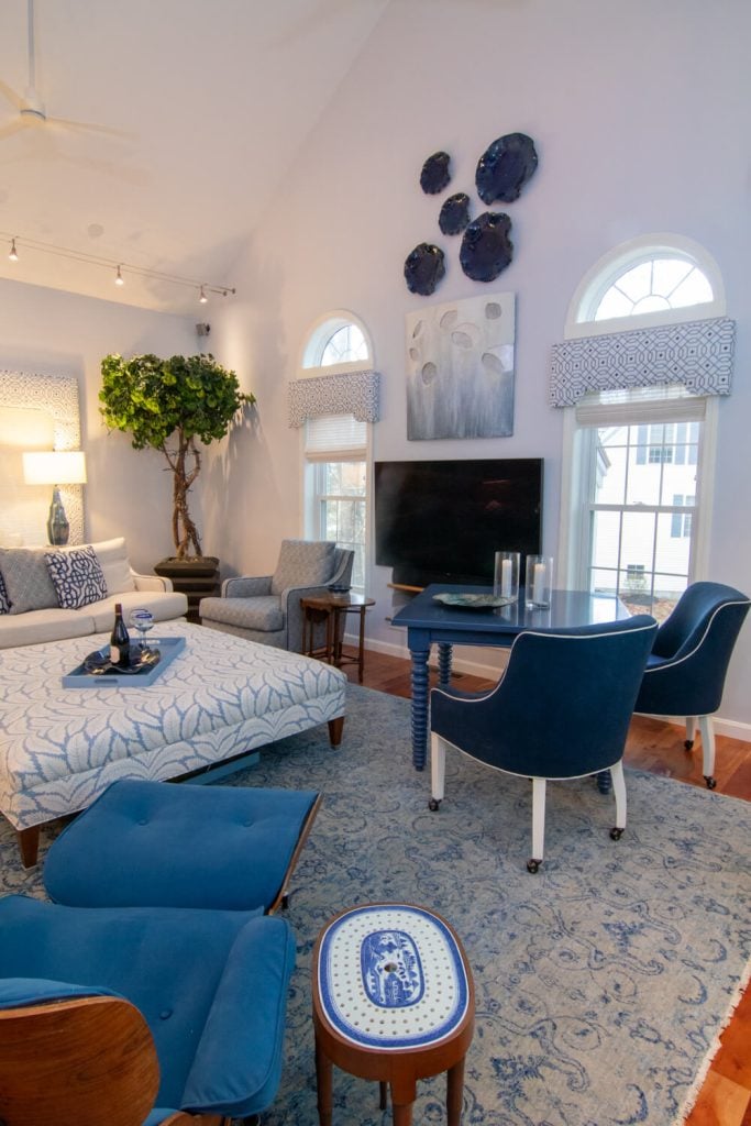 Living room with blue chairs, patterned ottoman, television and art